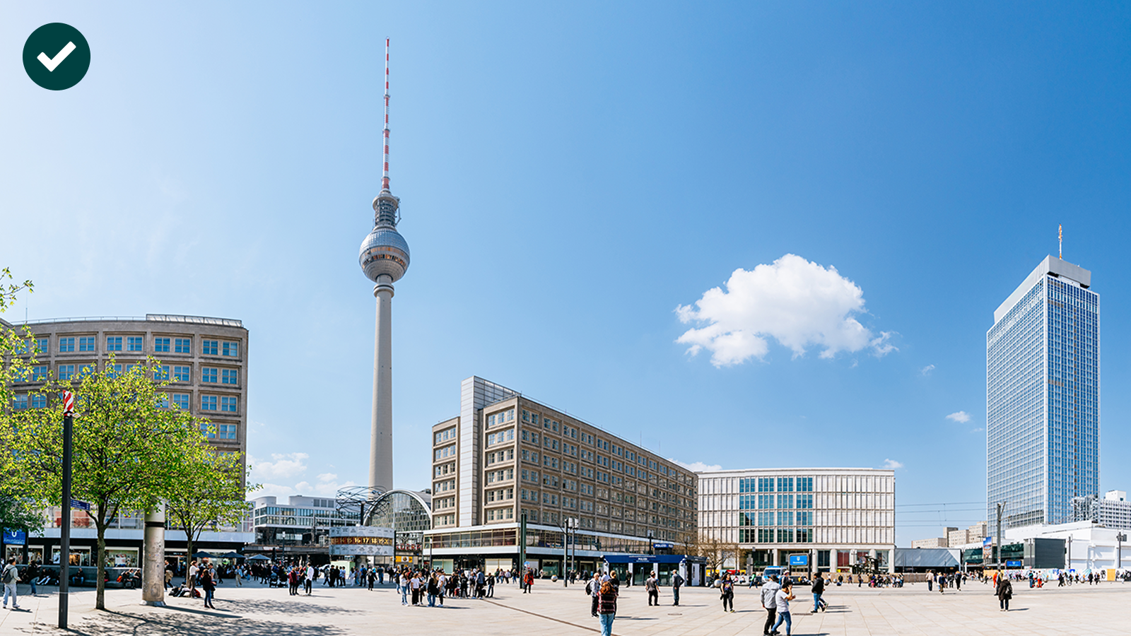 Weitläufiger Platz mit dem Fernsehturm im Hintergrund, umgeben von modernen Gebäuden, bei klarem Himmel.